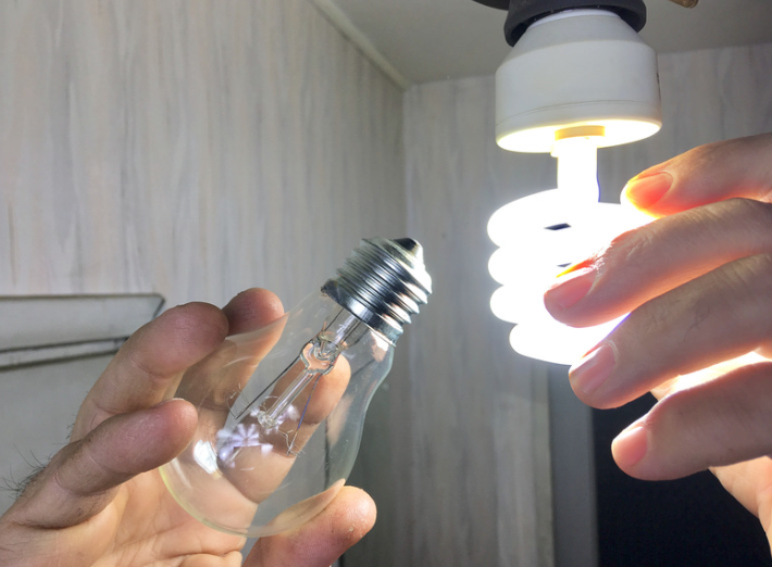 Image d'illustration : personne qui remplace une ampoule par un led